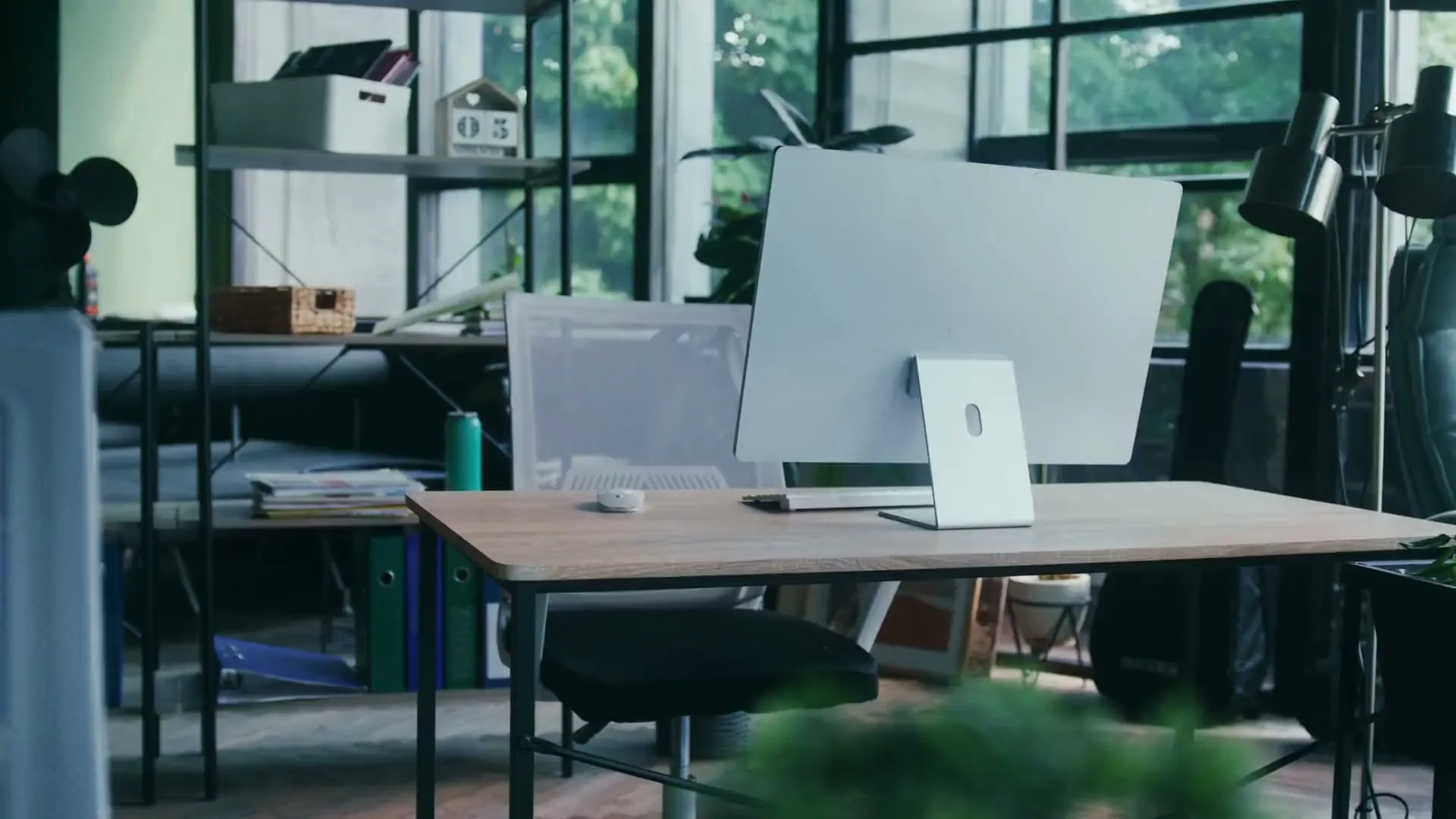 Escritório claro, com uma mesa de madeira, um computador e a cadeira vazia